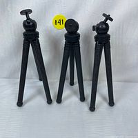 Three black mini portable camera tripods shown standing with legs extended and ball head with adjustable knob visible