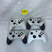 Photo of front side of four wireless gaming controllers featuring distinct designs and ergonomic shapes.