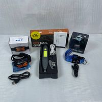 Full set showing pet nail grinder in middle with box, LED dog collar on right with box, anti-bark collar on left with box and cables
