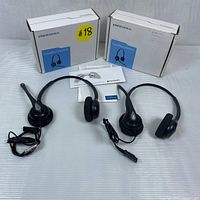 Two Plantronics Supra Plus HW261N headsets side by side with their original boxes and manuals laid on a white surface.