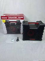 Front view of the ION Tailgater Tough speaker with included charging cable and silica gel packet, showing the box behind the speaker.