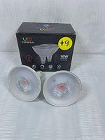 Two LED Par38 bulbs in front of box showing front clear lenses and LED reflector.