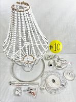 Photo showing the chandelier assembled with wooden beads and including all the installation hardware parts spread out on a white background.