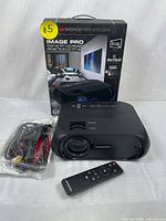 Front side of the black Monster Vision One Image Pro projector with original box behind it. Yellow sticker with #5 on projector and box.