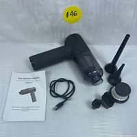 Photo showing the mini vacuum cleaner, USB charging cable, user manual, narrow nozzle attachments, and brush attachments arranged on a white surface with a yellow lot number sticker.