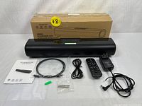 Photo showing soundbar, wireless speaker, remote, power adapter, cables, user manual, and original box.