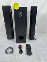 Bomaker Njord I sound bar set showing subwoofer, two satellite speakers, remote control, and cables neatly arranged on white surface with white background