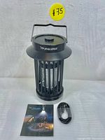 Black Palone electric bug zapper with user manual and charging cable arranged in front of neutral background.