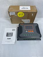 Photo of boxed PowMr PWM solar charge controller, user manual lying flat beside it. Clear view of controller front with LCD display and control buttons, two USB ports visible.