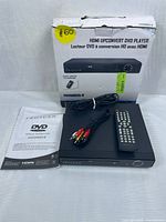 Photo showing Proscan PDVD6655 DVD player, original box, remote control, AV cables, and instruction manual from top-down view with cables coiled on top of the player.