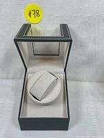 Front view of single watch winder case with transparent top lid and soft padded cushion interior.