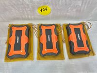 Three Fuzion digital professional scales with orange and black rugged casing, placed side by side on brown drawstring pouches on a gray surface.