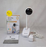 Chillaxbaby Giraffe Cam camera with flexible gooseneck clip base, power adapter, user's guide and original box shown front view.