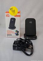 Photo of iQ Qi Wireless Charging Stand, its packaging, and a USB charging cable in front of the box.