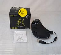 Delux M618 Plus RGB vertical ergonomic wired mouse with attached USB cable, original box, and user manual displayed on a white surface.