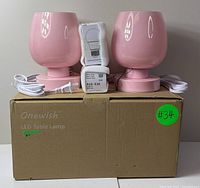Set of two pink Onewish LED table lamps shown with bulbs and box, cords attached to bases, on plain white background.