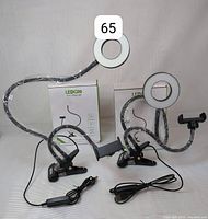 Two LEDGie ring lights out of the box showing flexible arms, clips, phone holders, and USB cables on a white background