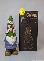 Full view of solar garden gnome statue showing front and box with product name and graphic illustration.