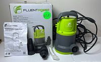 Fluentpower submersible sump pump with box, manual, fittings, and rope arranged on a flat surface.