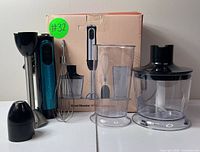Full view of hand blender set with motor unit, blending shaft, whisk, blending beaker, chopper attachment, and original box.