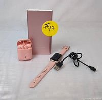 Photo showing the pink Jugeman Q23 wireless earbuds in charging case, PowerAdd power bank, and pink smartwatch with band and USB charging cable.