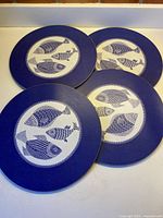 Four indigo fish design hot plates displayed