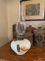 Full view of lamp showing milk glass base, hand painted flower, brass fittings, clear glass chimney