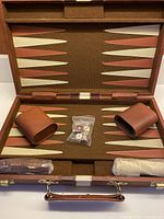 open backgammon case showing playing surface, dice cups, wrapped checkers, dice, doubling cube