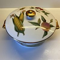 Casserole with lid on, showing fruit design and gilt handles