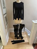 Full outfit on mannequin: bodysuit with corset, boots on floor, gloves laid out