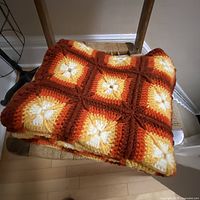 Folded crochet blanket on chair shows color palette and texture