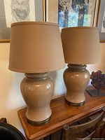 Both coffee/caramel glass lamps with shades on wooden table