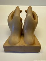 Front view of wooden hands sculpture on base