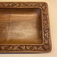 Top view of solid hardwood shallow bowl showing leaf carving around rim
