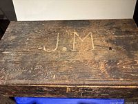 Top view of antique wooden storage box showing carved initials J.M.