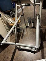 Overview of the Gazelle manual elliptical machine showing the gray metal frame, foot pedals, and handle bars on a hard floor surface.