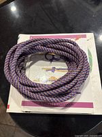 Coiled purple and white braided rope resting on hardcover knot tying book