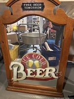 Full view of large oval wooden frame mirror with 'Ice Cold Beer' text and beer mug graphics in mirror reflection, showing beer signage theme.