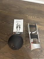 Photo showing Marcy wrist and forearm developer, Bollinger medicine ball, and Bollinger instruction manual on wooden floor