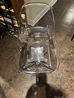 Top view of modern clear acrylic chair seat showing transparent material and metal base attachment.