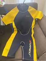 Blue and yellow shorty neoprene wetsuit laid flat showing front
