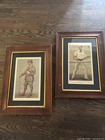 Two framed Vanity Fair prints of early 20th century tennis players with wood frames, black and gold matting, placed on wood floor.