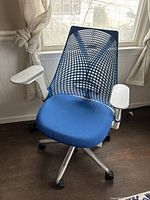 Front view of the blue and white ergonomic office chair with mesh back and cushioned seat near window.