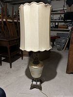 Full view of the lamp showing the tall fabric shade and the intricately detailed base with cherub figure.