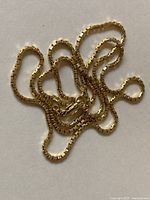 Coiled 14k gold box chain on white background