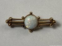 Front view of gold bar brooch with central round opal showing detail of wire and ball design
