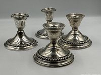 Four sterling silver candlestick holders (two by Gorham, two by Watrous) arranged in group