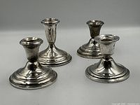 Four candlestick holders (two tall, two short) displayed on flat surface