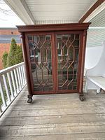 Front view of mahogany bookcase showing glass doors with geometric muntins and carved claw feet