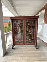 Front view of closed bookcase showing double glass-paneled doors, carved columns and claw feet